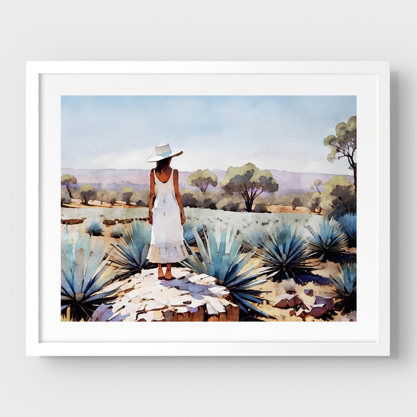 White framed artwork of a woman in a white dress and hat standing in an agave field.