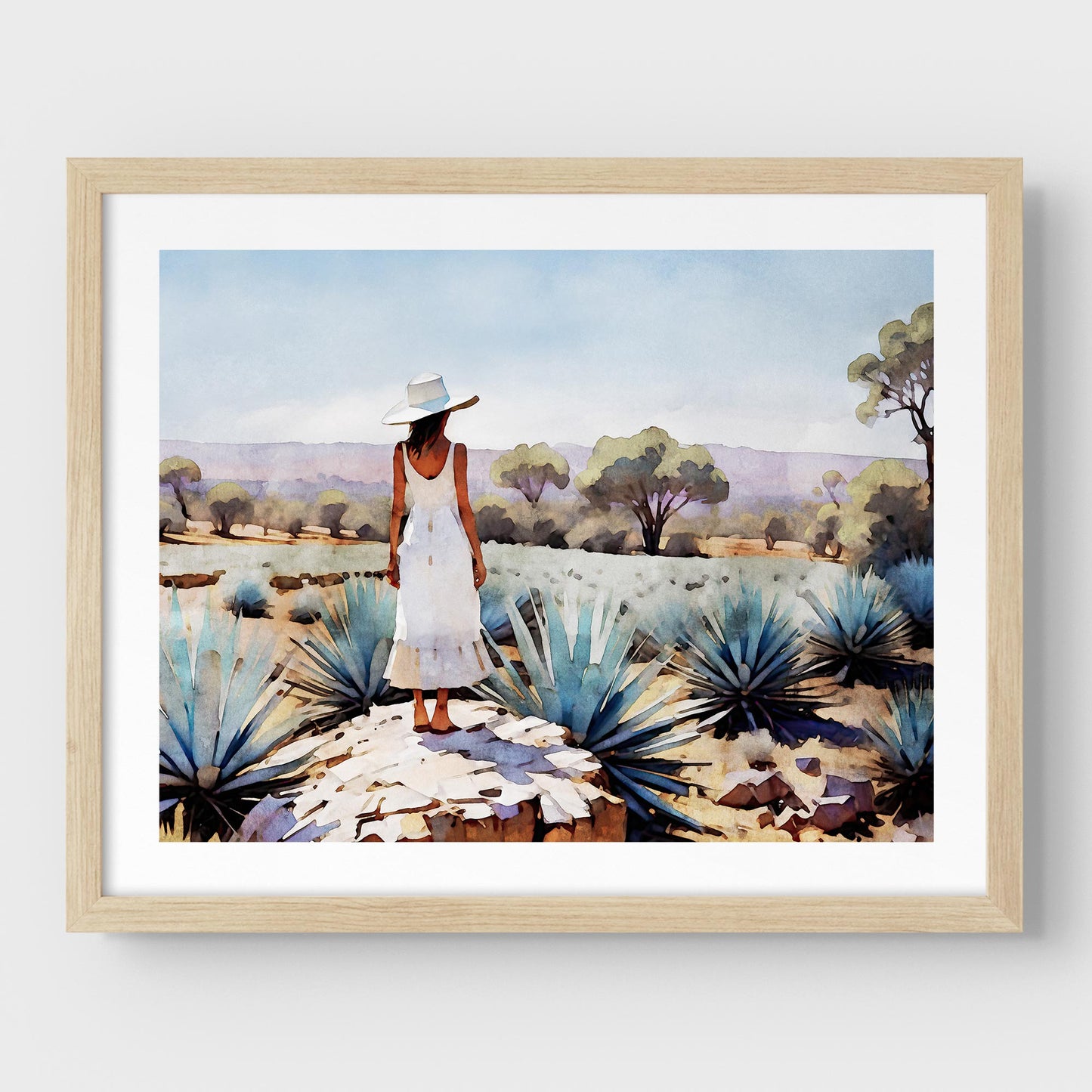 Natural wood framed artwork of a woman in a white dress and hat standing in an agave field.