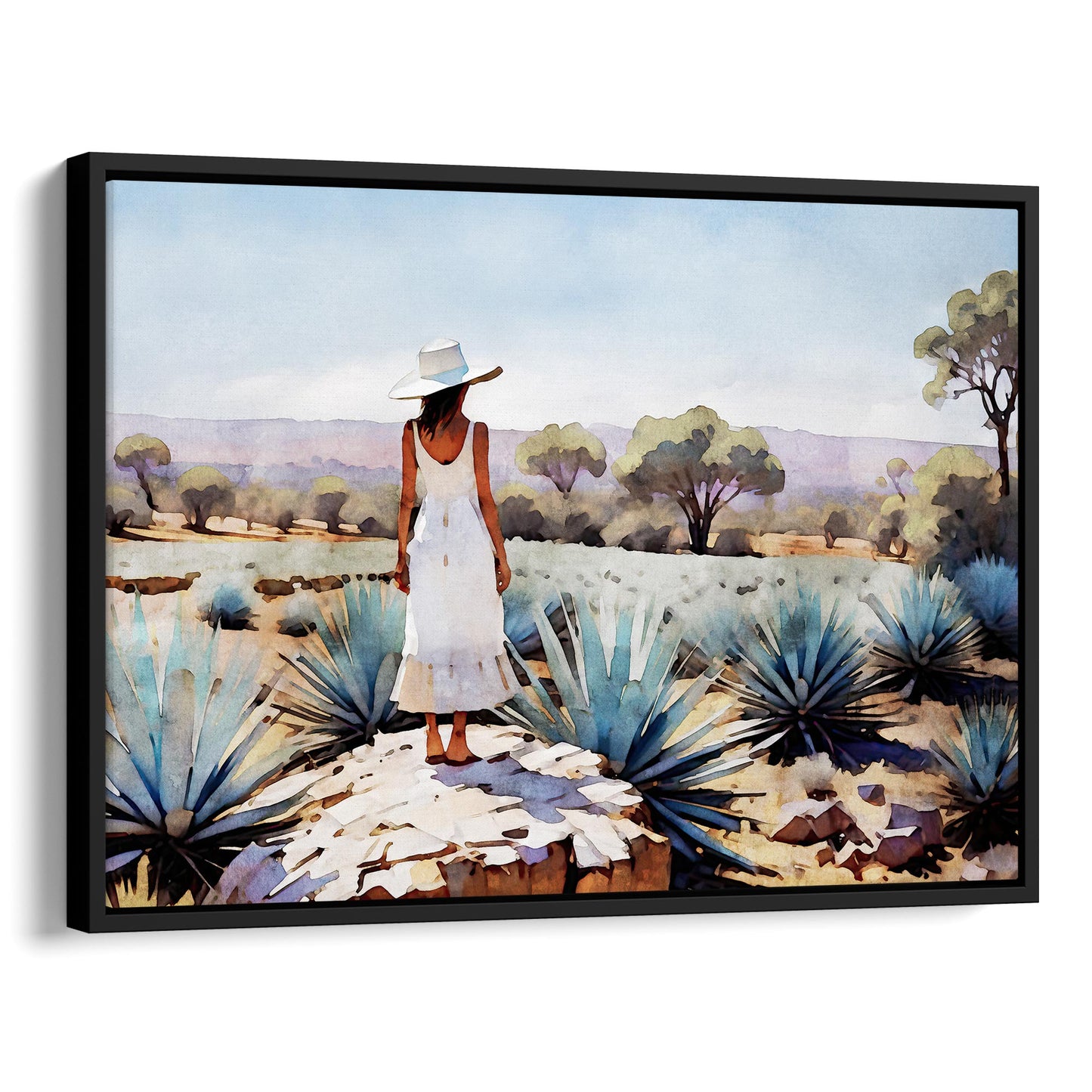 Black framed canvas print of a woman in a white dress and hat standing on a rock in an agave field with trees and mountains in the background.