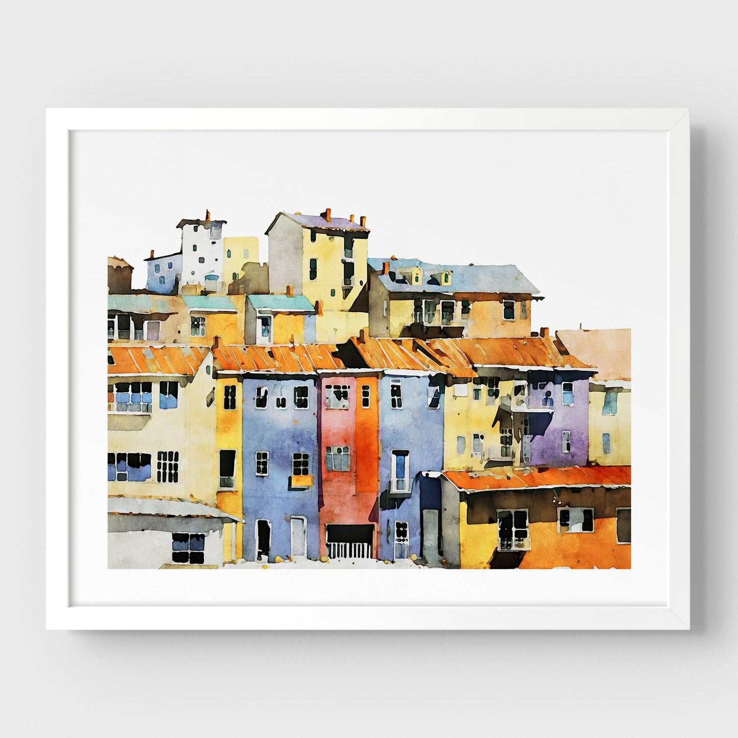 Framed watercolor painting of a colorful hillside village with vibrant buildings, mounted on a white wall with a white frame.