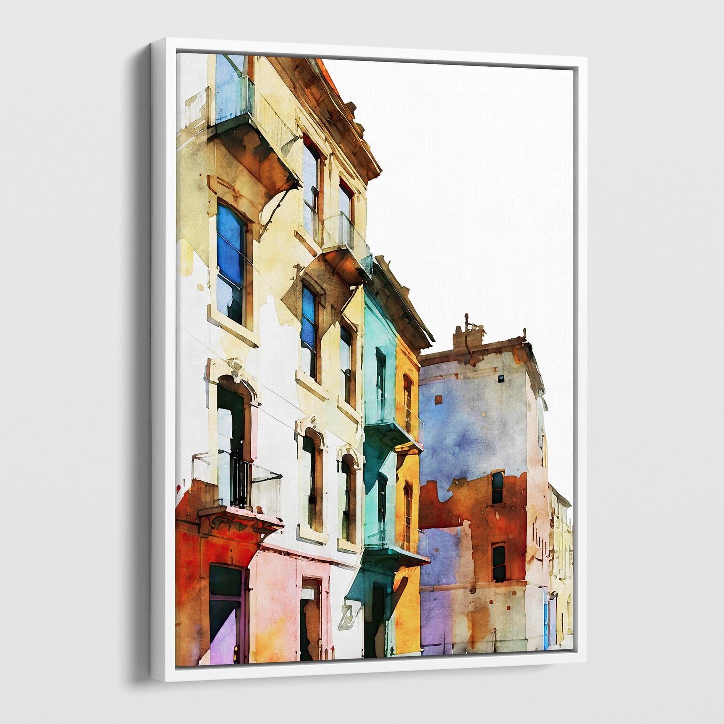 Framed canvas print of a watercolor painting showing colorful buildings with pastel facades, set in a white frame.
