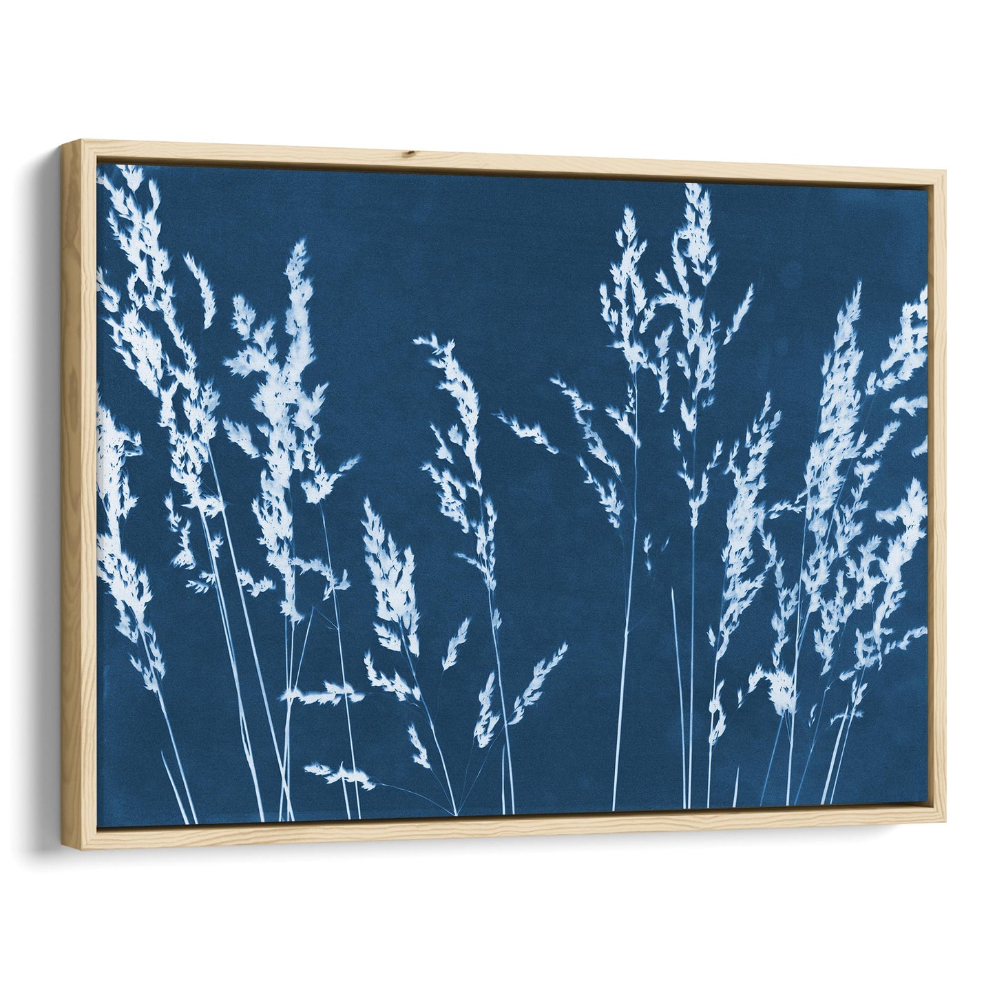 Framed cyanotype print featuring white wild grass silhouettes against a deep blue background, enclosed in a sleek natural wood frame.