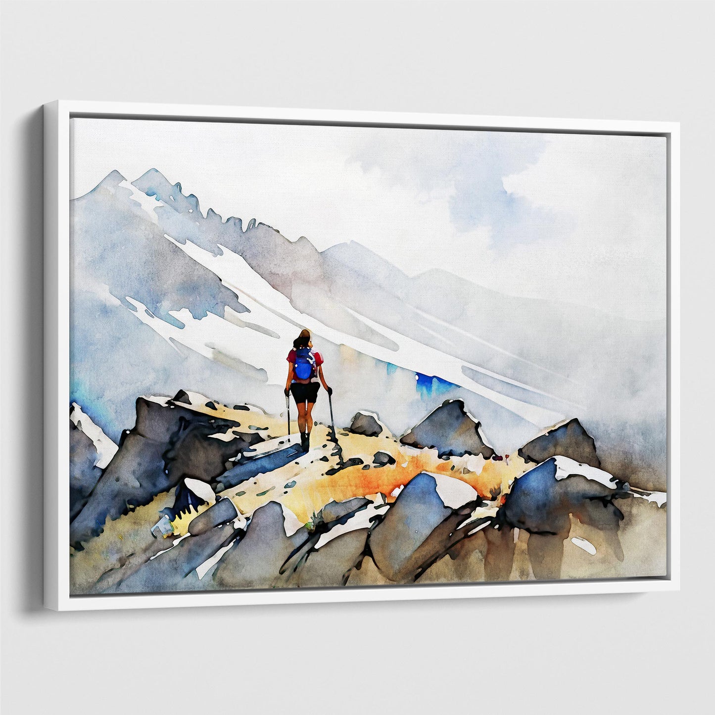 White framed canvas print of a hiker with trekking poles and a blue backpack on a rocky mountain path, with misty snow-covered peaks in the background.