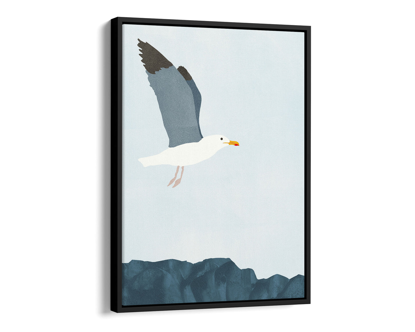 Black framed canvas illustration of a seagull soaring above a rocky shoreline, with its wings spread wide against a pale blue sky.