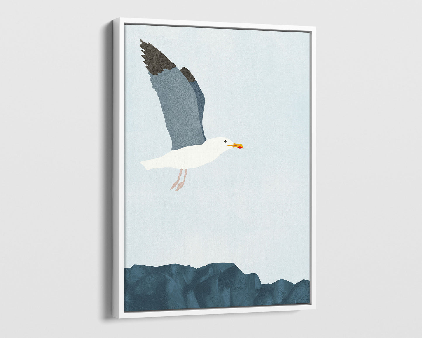 White framed canvas illustration of a seagull soaring above a rocky shoreline, with its wings spread wide against a pale blue sky.