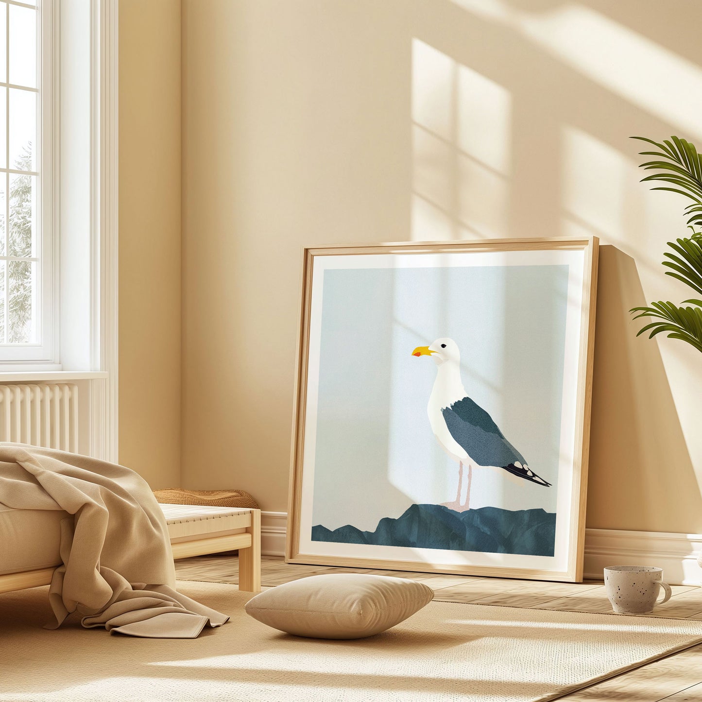 Framed illustration of a seagull on a dark blue rock, leaning against a beige wall in a sunlit room with warm neutral decor and a floor cushion.