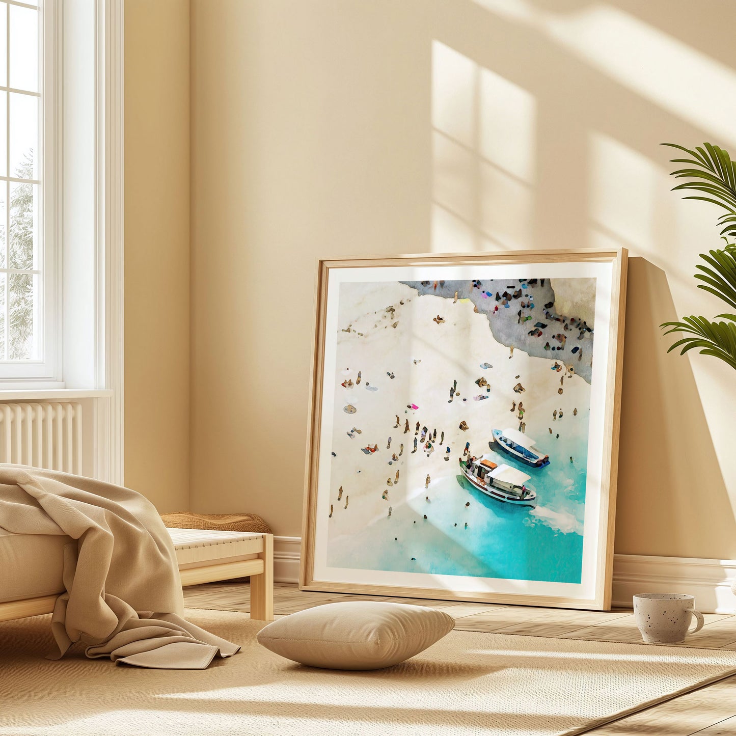Framed artwork in a natural wood frame, resting on the floor of a sunlit room with beige tones, featuring a watercolor-style beach scene with two boats and people on the shore.
