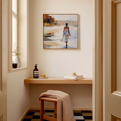 A square format framed watercolor painting of a woman walking along the beach hangs on a wall in a minimalist bathroom.