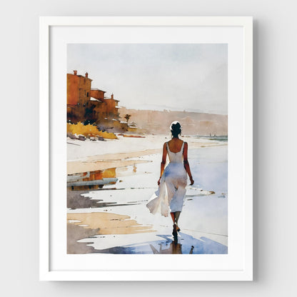A white framed watercolor painting of a woman in a flowing white dress walking along the shoreline at sunset. 