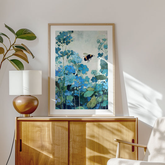 Framed artwork of blue flowers and a bee on a wall above a wooden cabinet.