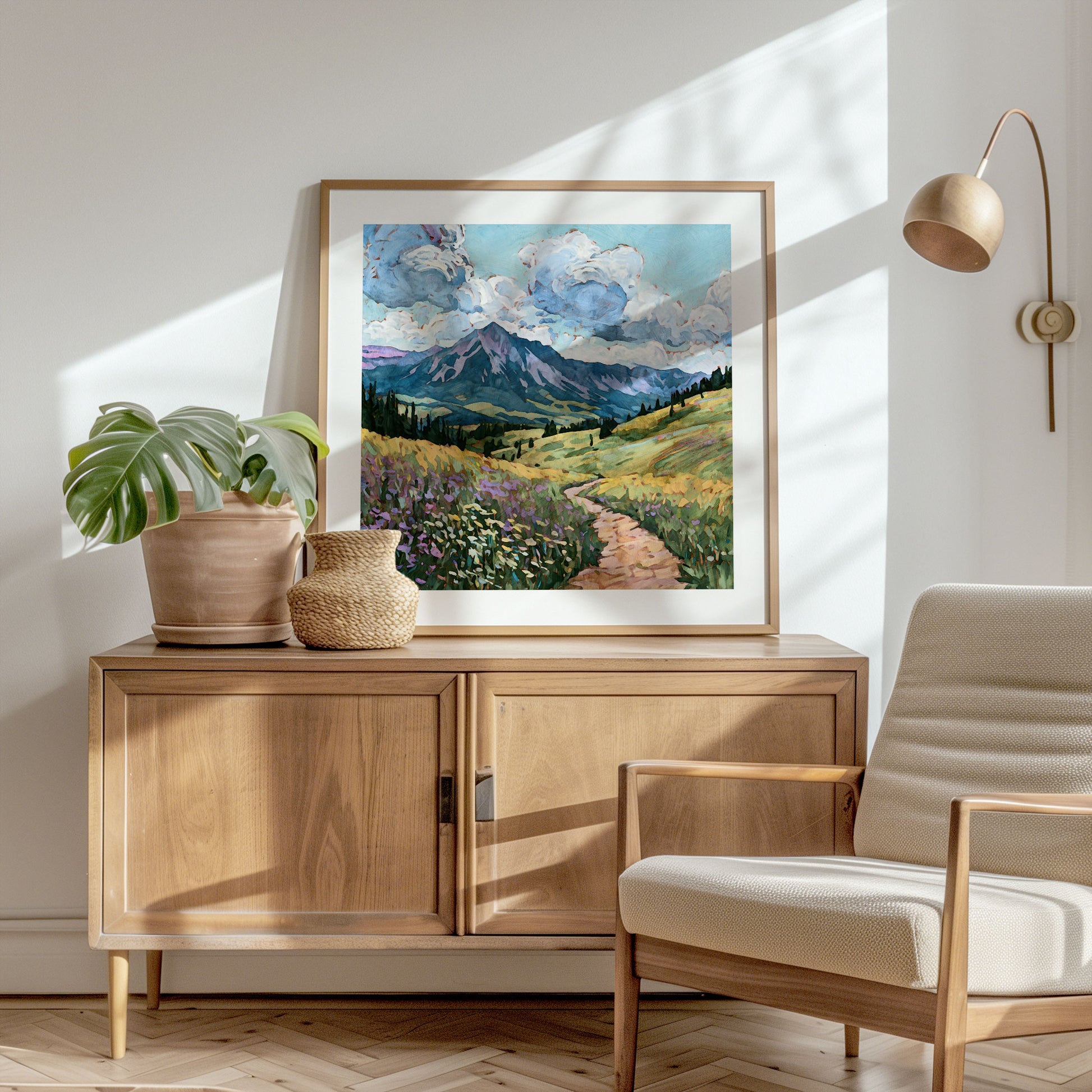 Wooden sideboard with a landscape painting, plant, and chair in a bright room.