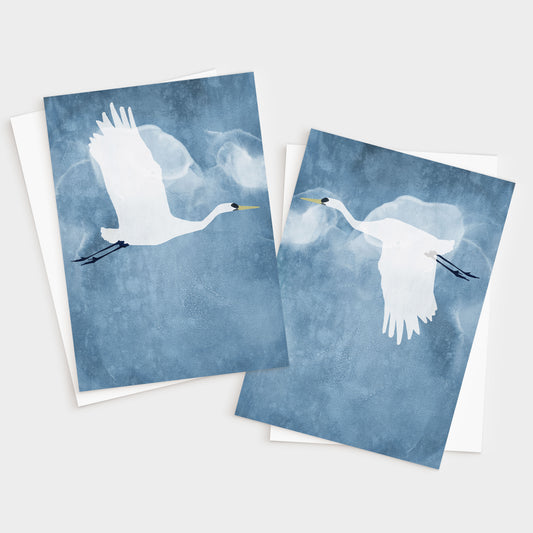 Set of two greeting cards featuring minimalist illustrations of white egrets in flight against a textured blue sky, one with wings raised and the other with wings down, each paired with a white envelope.