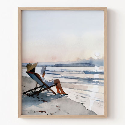 Framed artwork of a person sitting on a beach chair by the water.