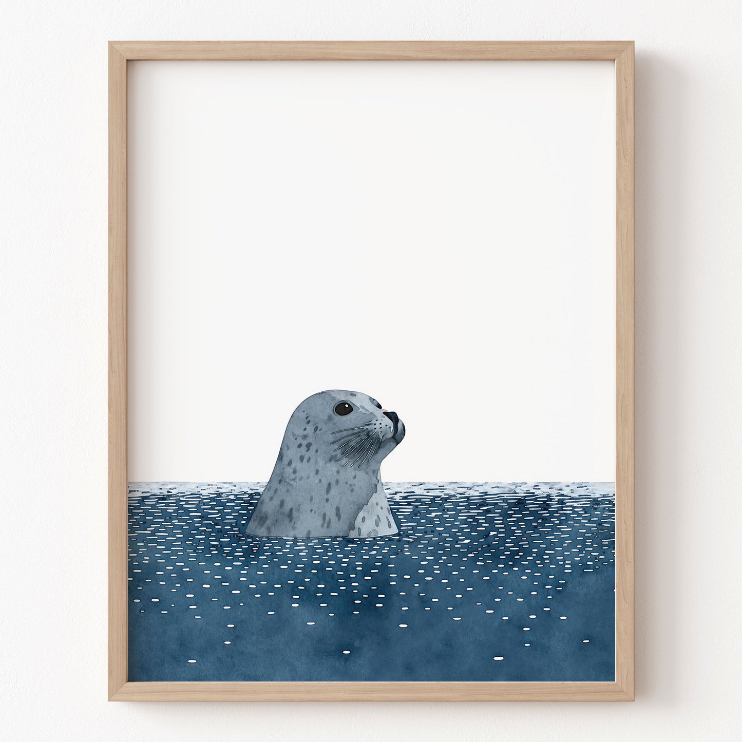 Framed artwork of a seal peering out from water on a white wall