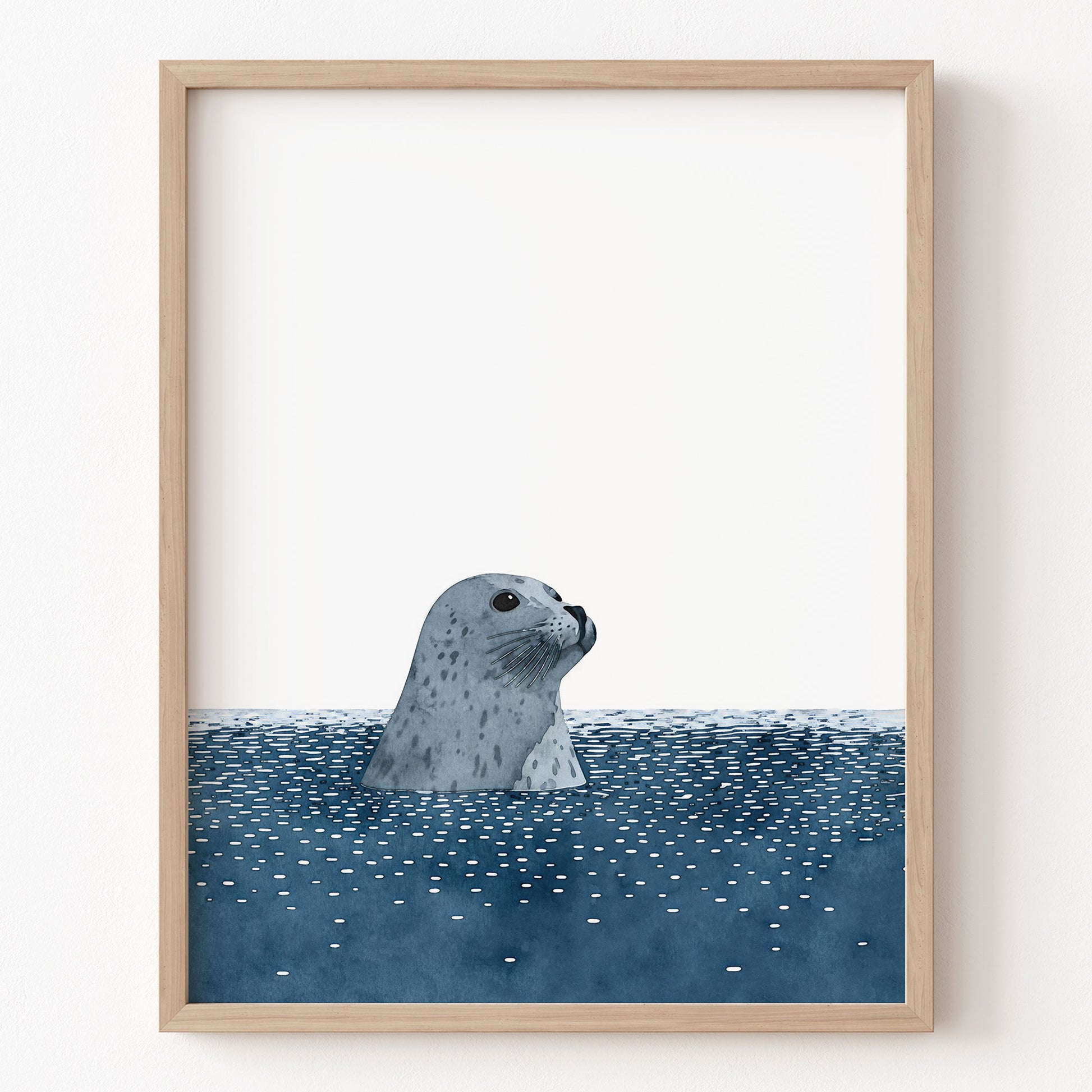 Framed artwork of a seal peering out from water on a white wall