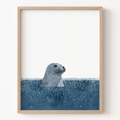 Framed artwork of a seal peering out from water on a white wall