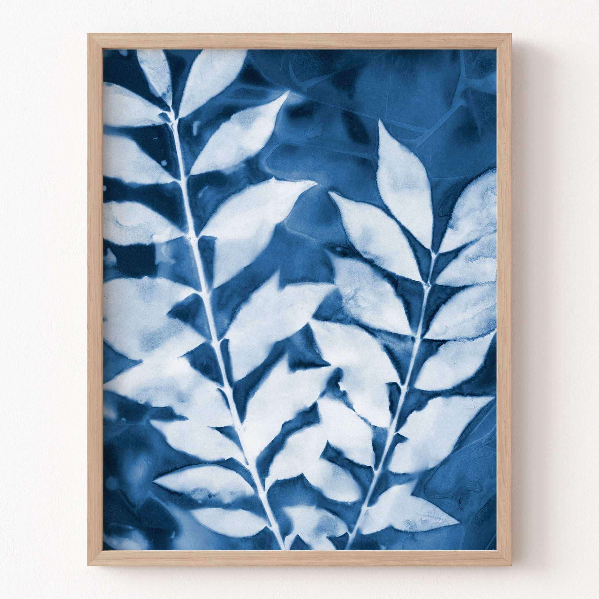 Framed artwork with blue and white leaf pattern on a white wall