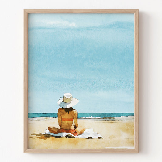 Framed artwork of a person sitting on a beach with a blue sky.