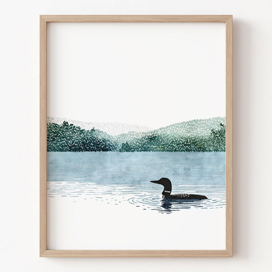 Framed artwork of a loon on a lake with trees in the background