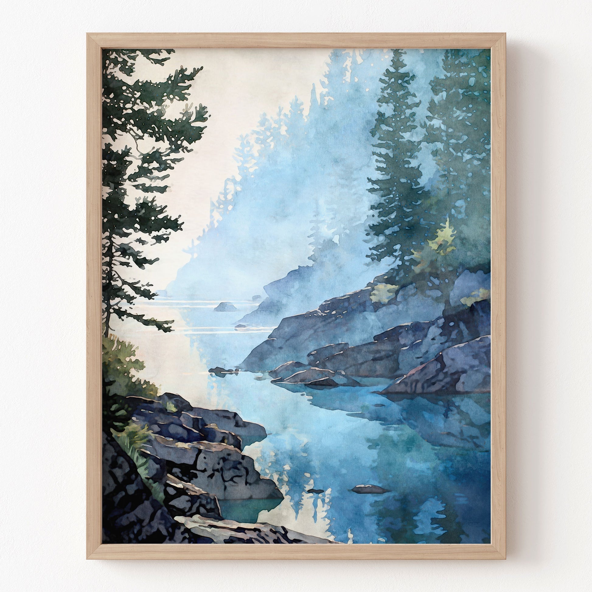 Framed artwork of a mountain landscape with a lake and trees on a white wall.