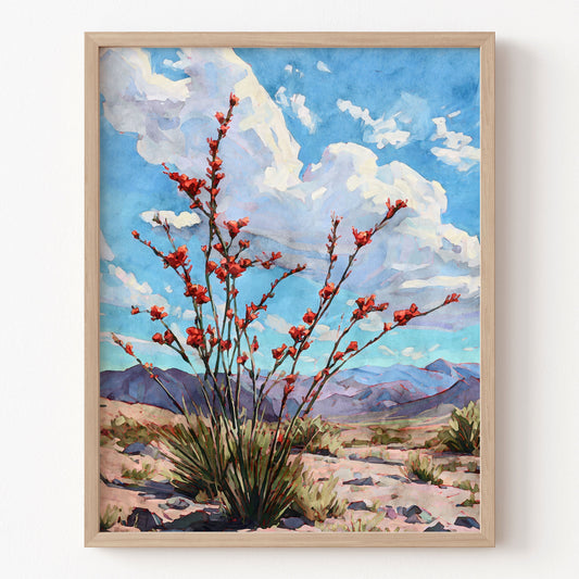 Framed artwork of a desert scene with red flowers, blue sky, and mountains.