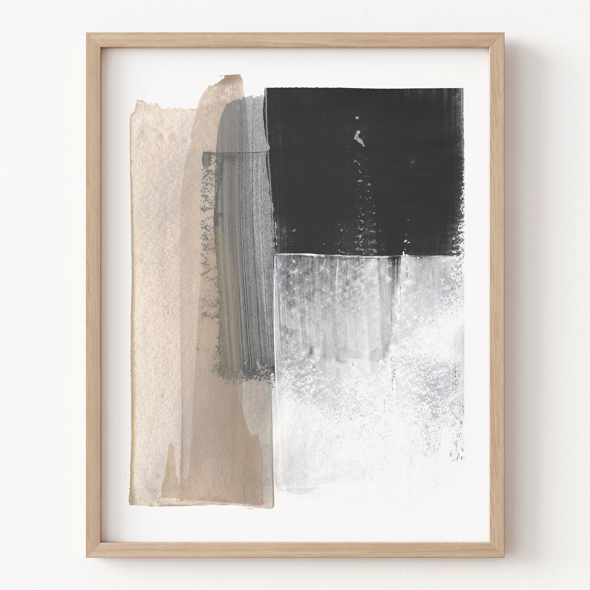 Abstract art print with black, white, and beige brush strokes in a wooden frame on a white wall.