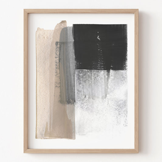 Abstract art print with black, white, and beige brush strokes in a wooden frame on a white wall.