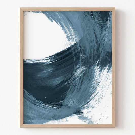 Framed abstract art print with blue and white brush strokes on a white wall.