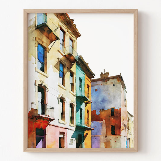 Framed artwork of colorful buildings on a white wall