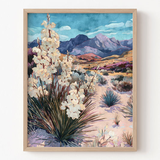 Framed artwork of a desert landscape with white flowers and mountains.
