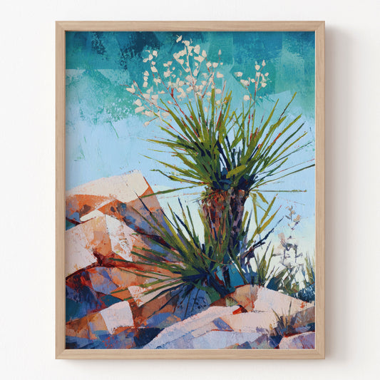 Framed artwork of a desert landscape with plants and rocks on a white wall.