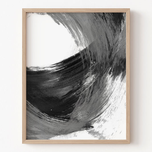 Framed abstract art print with black and white brush strokes on a white wall.
