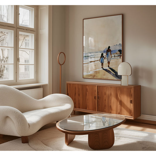 Minimalist living room with a white curved sofa, glass coffee table, wooden sideboard, and a large framed beach painting on the wall.