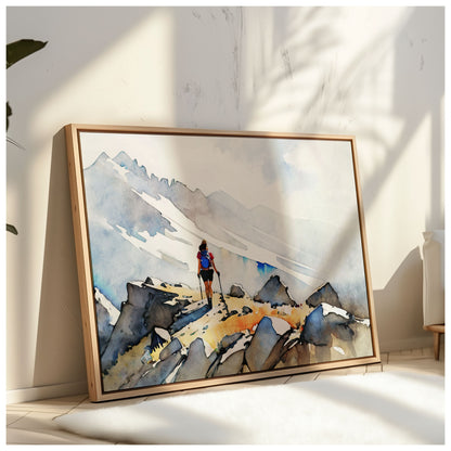 A framed artwork of a hiker on a rocky mountain path leans against a sunlit wall, with soft shadows cast by nearby plants.