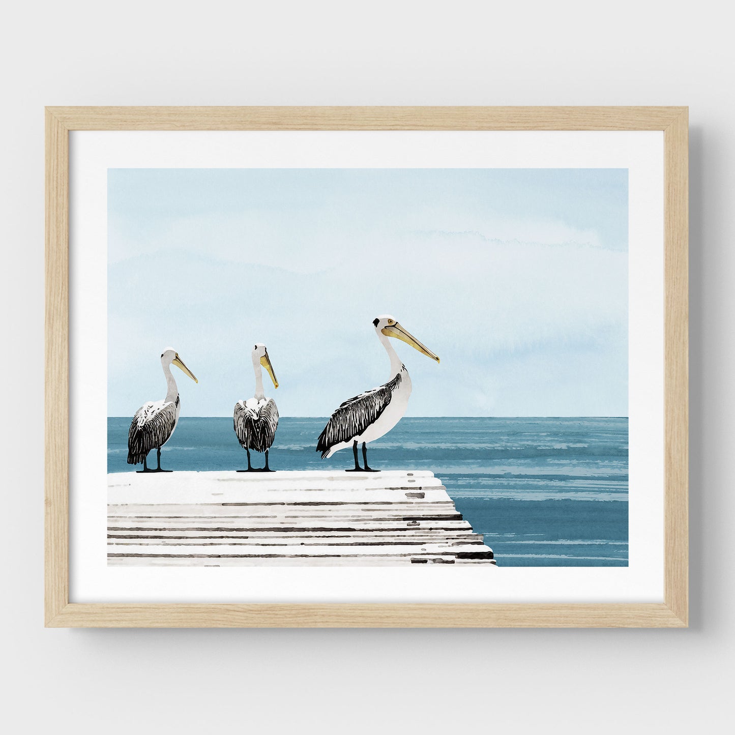 Natural wood framed illustration of three pelicans standing on a weathered dock above calm blue ocean water, with a soft, pale blue sky in the background.