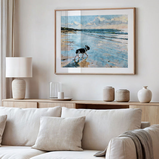 Framed pied French Bulldog beach watercolor art displayed in a styled interior with soft blue and sandy neutral tones.