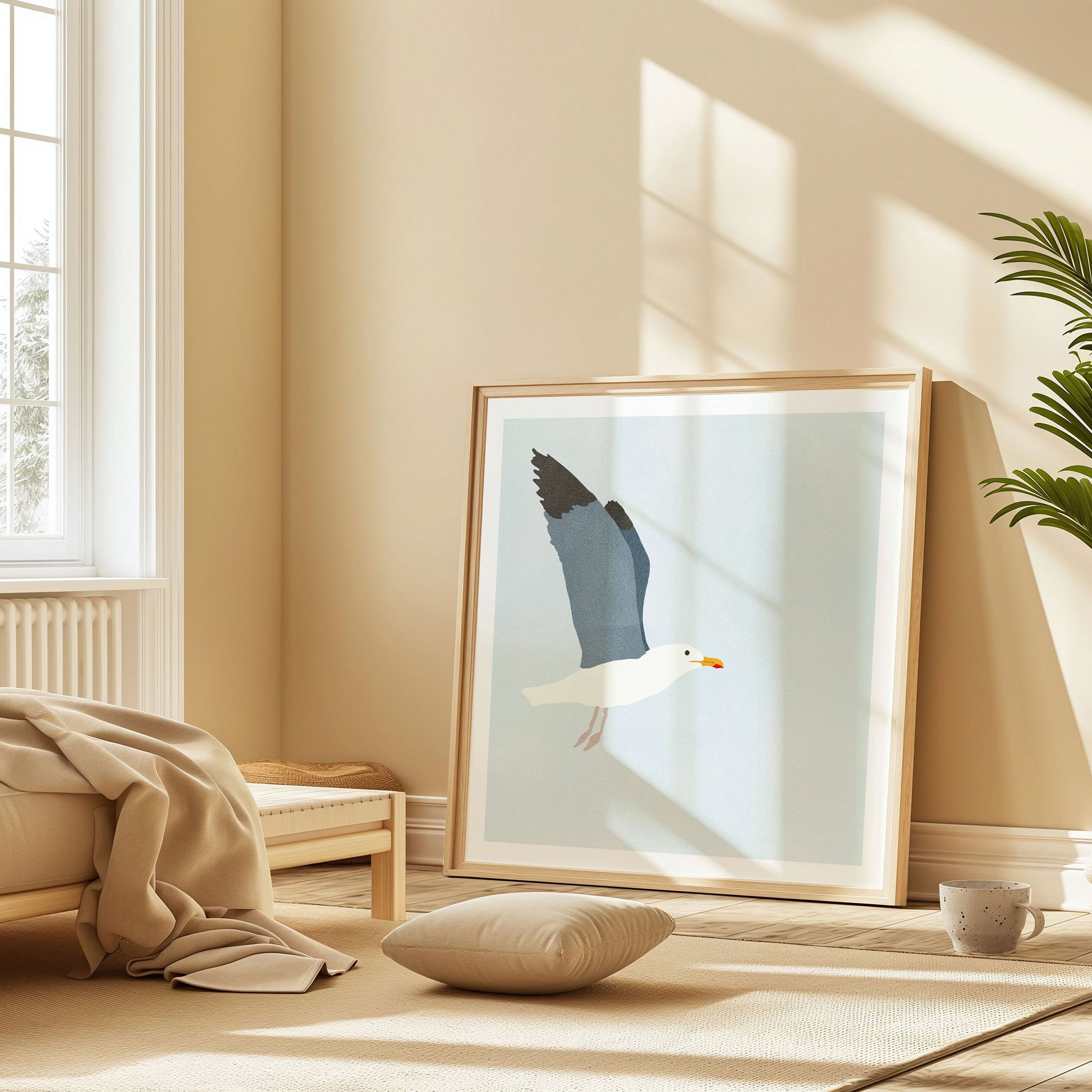 Framed minimalist illustration of a seagull in flight, leaning against a wall in a sunlit bedroom with warm beige tones, a floor cushion, and soft textiles.