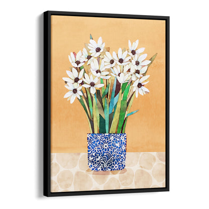 Black framed canvas artwork featuring white flowers with dark centers in a blue patterned vase on a beige patterned surface with an orange background.