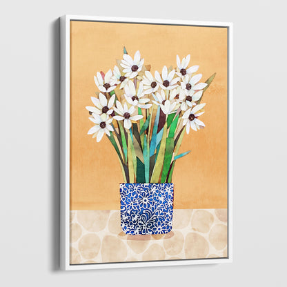 White framed canvas artwork featuring white flowers with dark centers in a blue patterned vase on a beige patterned surface with an orange background.