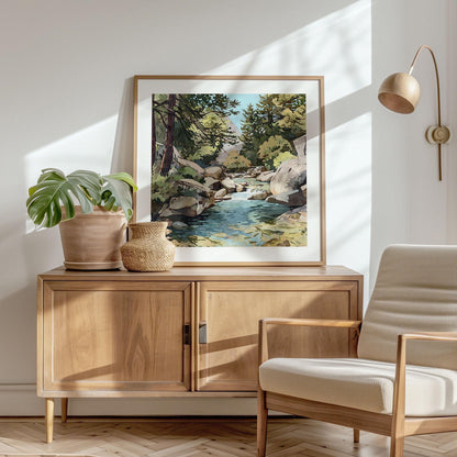 Framed painting of a rocky stream with pine trees and mountains displayed on a wooden sideboard, styled with a potted plant, woven vase, and modern chair in a sunlit, minimalist living space.