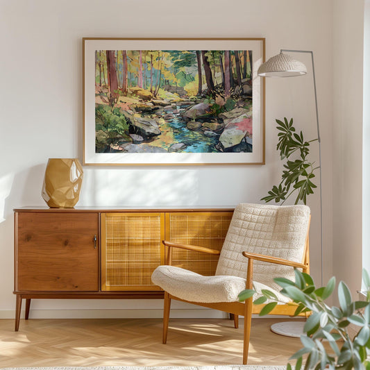 Framed watercolor-style forest landscape art print hangs above a mid-century modern wooden sideboard, with a cream armchair, floor lamp, and potted plant completing the cozy, sunlit living room setting.
