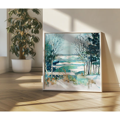 Framed watercolor winter landscape featuring bare trees, evergreens, and a snow-dappled field in teal, blue, and white hues, leaning against a sunlit wall with a potted plant nearby on wooden flooring.