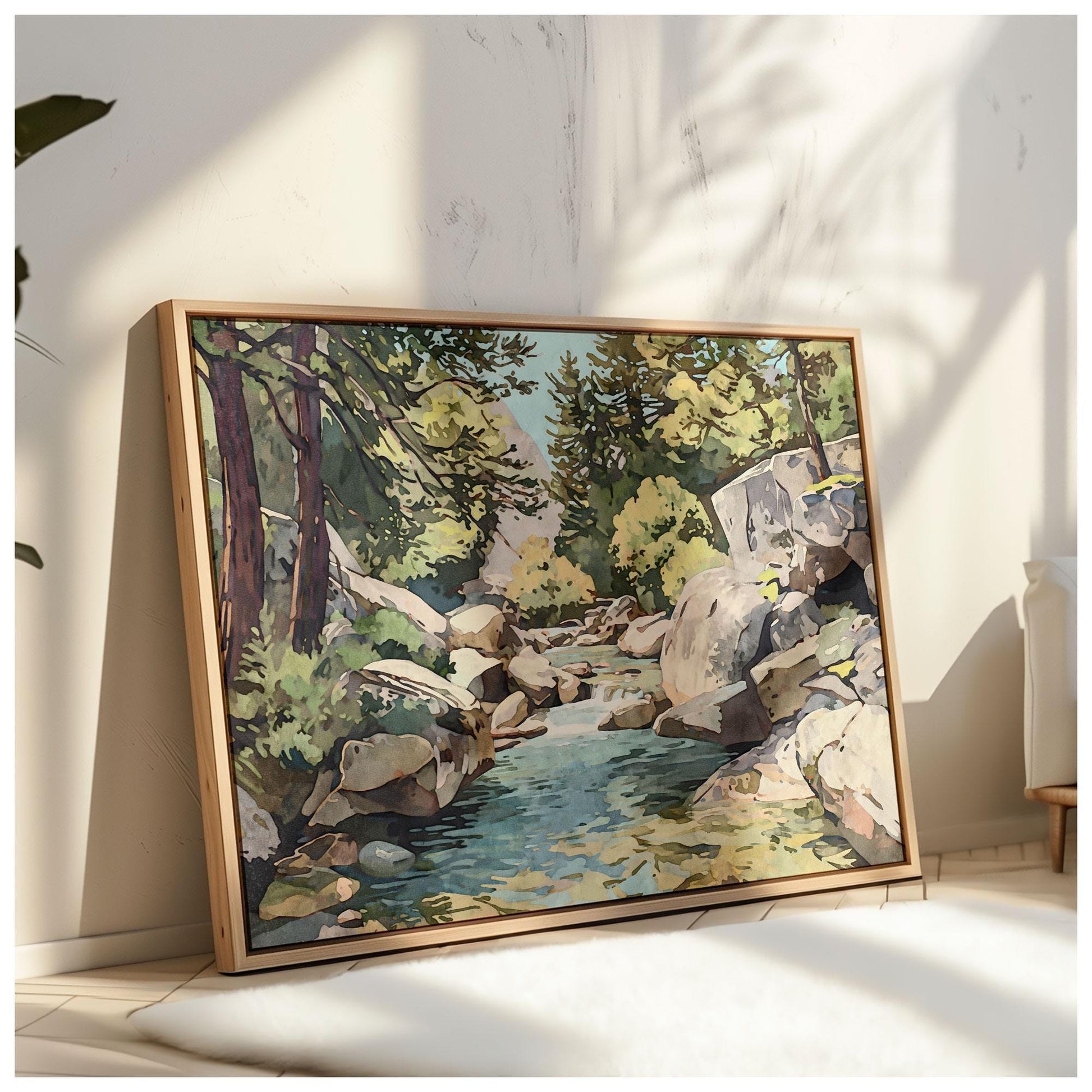 Framed painting of a rocky mountain stream with pine trees and sunlight filtering through, leaning against a textured white wall on the floor, bathed in warm natural light with soft shadows of plants.