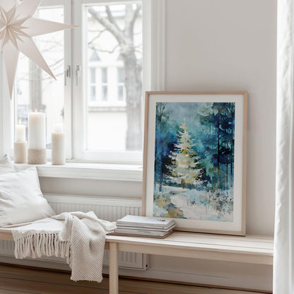 A framed watercolor print of a glowing white Christmas tree in a snowy blue-green forest rests on a light wooden bench in a cozy, minimalist room. Soft winter light filters through the window, with white candles, a knit throw, and neutral pillows creating a calm, Scandinavian-inspired holiday atmosphere.