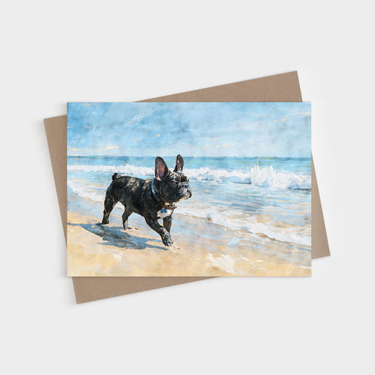 Brindle French Bulldog walking on a sandy beach with ocean waves behind, printed on a blank folded greeting card with kraft envelope.