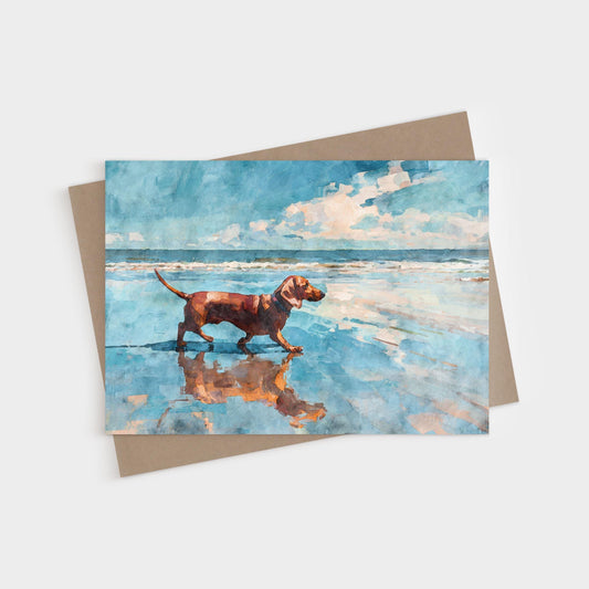 Brown Dachshund standing in reflective beach water under a bright blue sky, shown on a blank folded greeting card with kraft envelope.